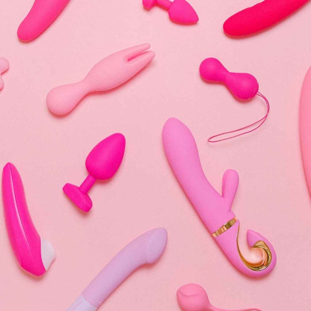 Forskellige pink vibratorer og anal plugs arrangeret på lyserød baggrund, sexlegetøj i silikone til klitoris og anal stimulering