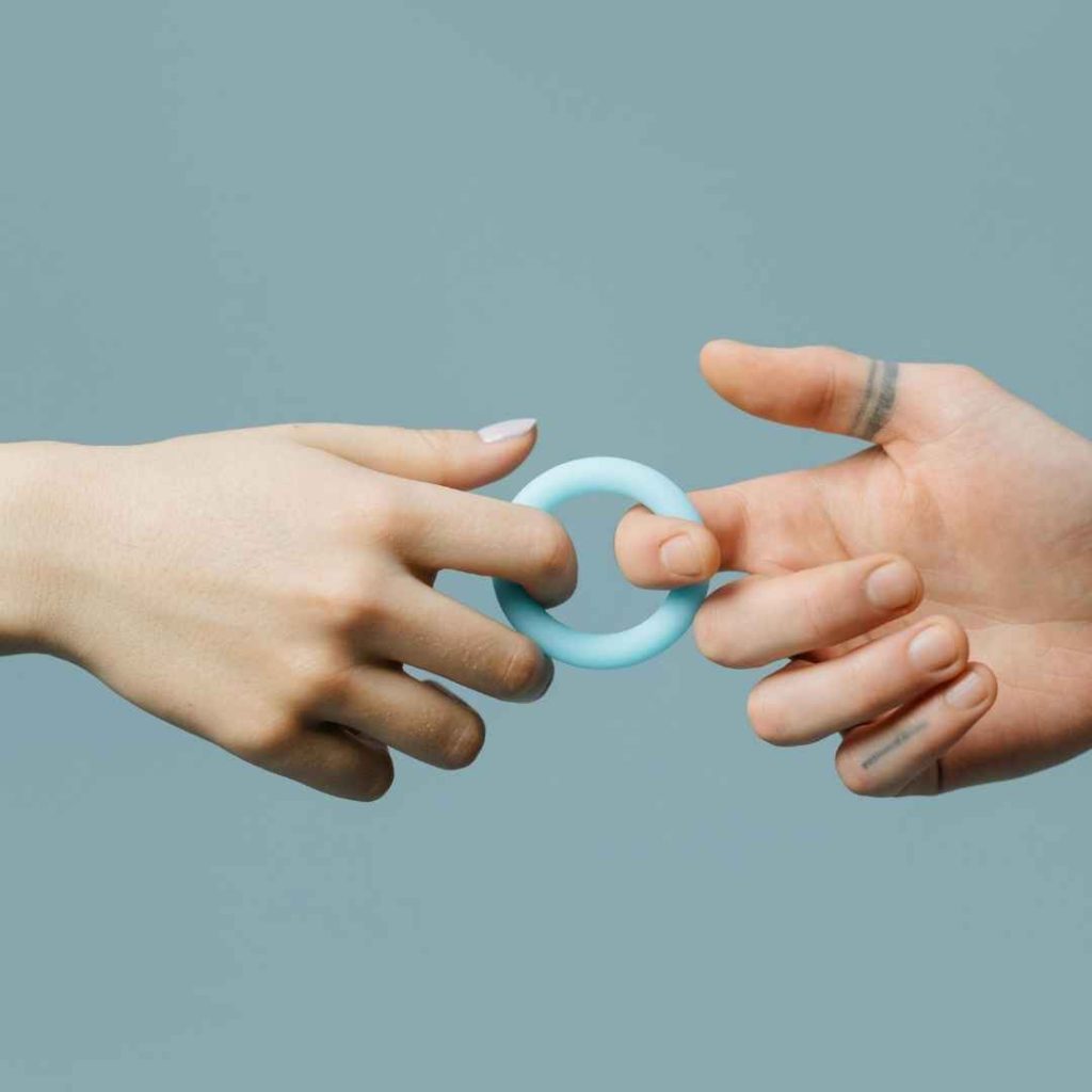 To hænder udveksler en lille blå klitorisstimulator, kompakt sexlegetøj i silikone til diskret stimulering