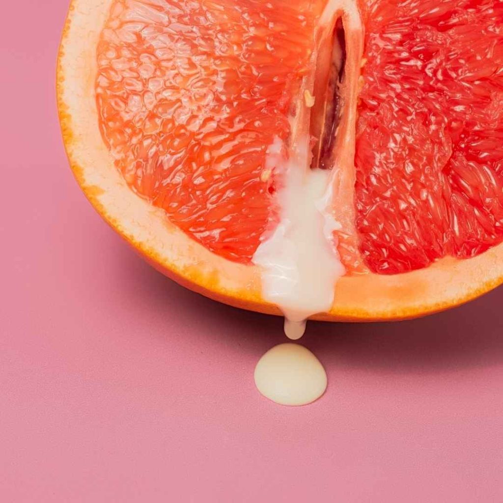 Halv grapefrugt med hvid creme i midten på lyserød baggrund, sensuel reference til oralsex og intim nydelse